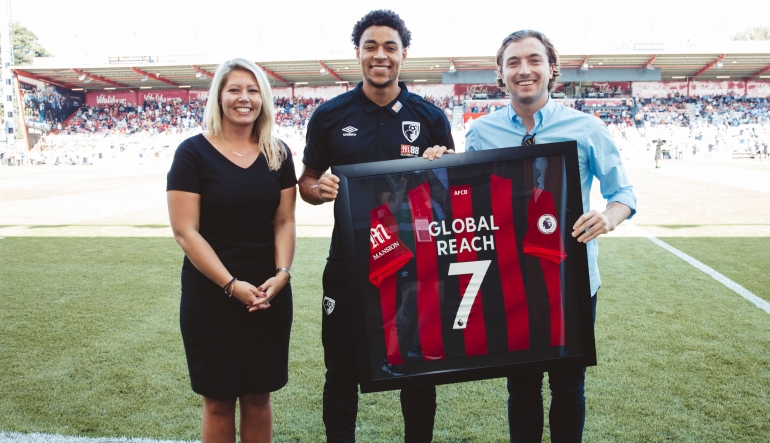 AFC Bournemouth Partnerships Manager Amy Marks and new signing Anaut Danjuma present a commemorative shirt to Joseph Stevens of Global Reach to mark the company’s arrival as an official corporate supporter and supplier of the Cherries as well as an official partner of the club’s commercial arm AFC Business